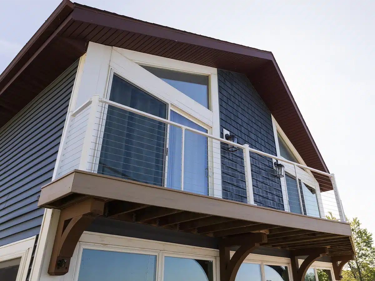 blue lakefront house with white cable railing on second floor balcony