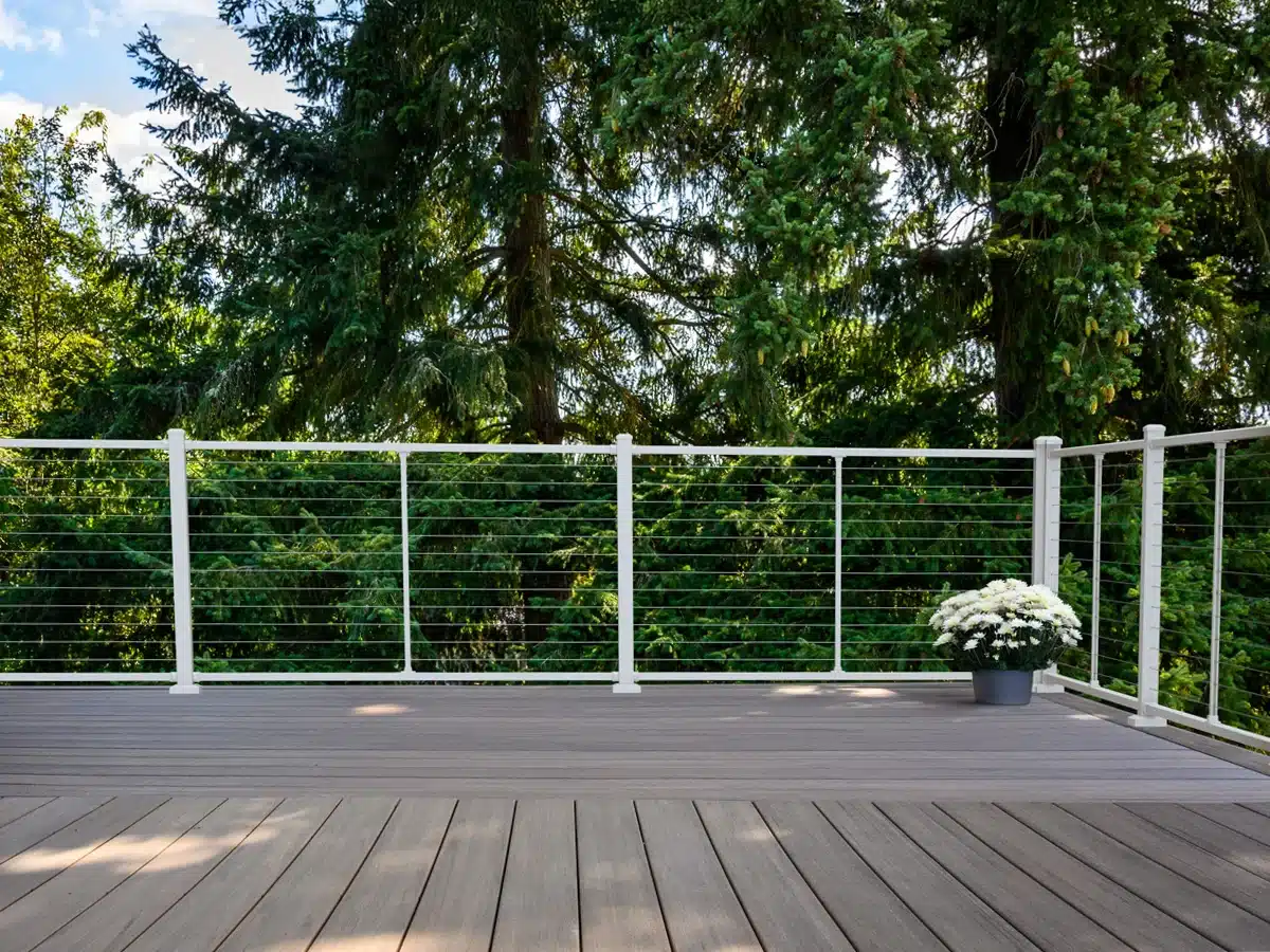 large backyard deck in wooded area with white cable railing