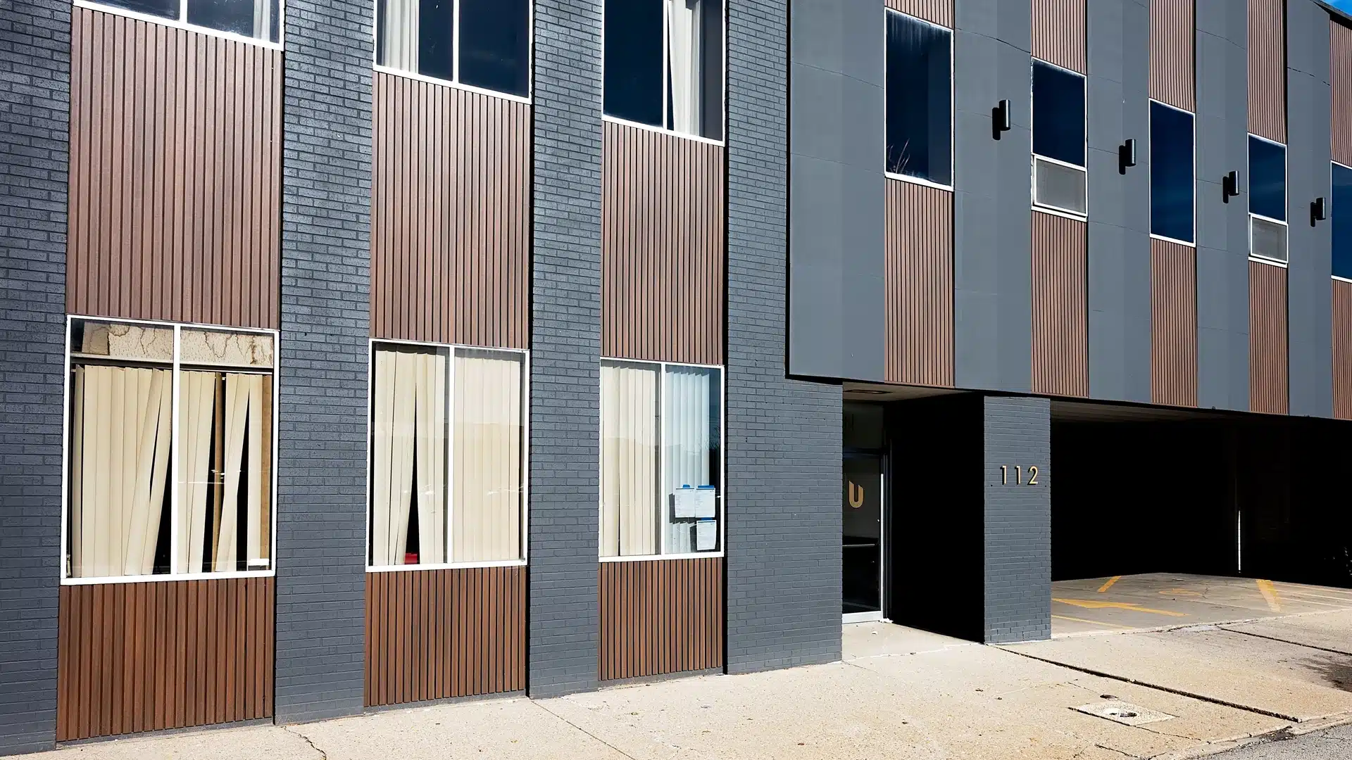 hotel with rows of windows, black painted brick and brown wood cladding