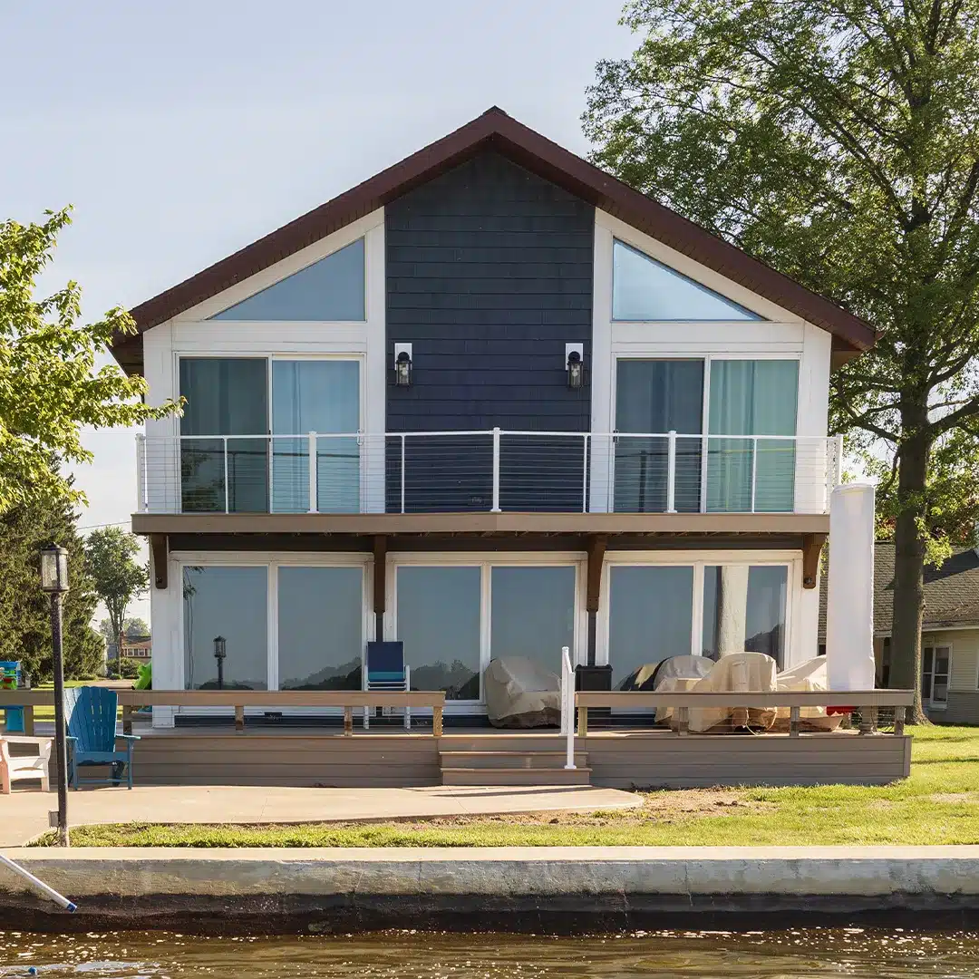 front side of blue lake house with white railing and trim